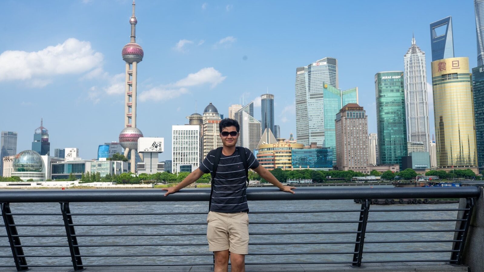Junger Mann steht vor Skyline in Shanghai
