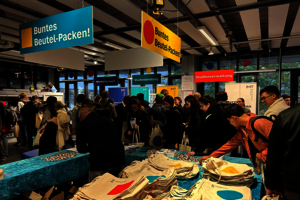 Eine Menschenmenge vor einem Tisch mit vielen Stoff-Beuteln.