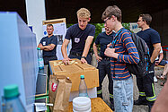 Mitarbeiter erklärt Besuchern etwas an einem Stand.
