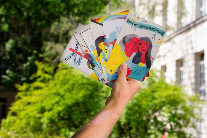 Eine ausgestreckte Hand hält bunte Postkarten in der Hand. „Erste mit Hochschulabschluss“ steht auf der ersten Karte geschrieben.