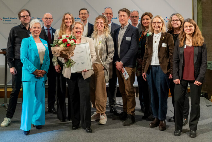 Gruppenbild von 14 Männern und Frauen unterschiedlichen Alters, smart casual gekleidet