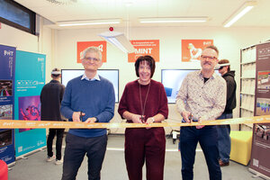 Drei Personen schneiden ein orangenes Band durch