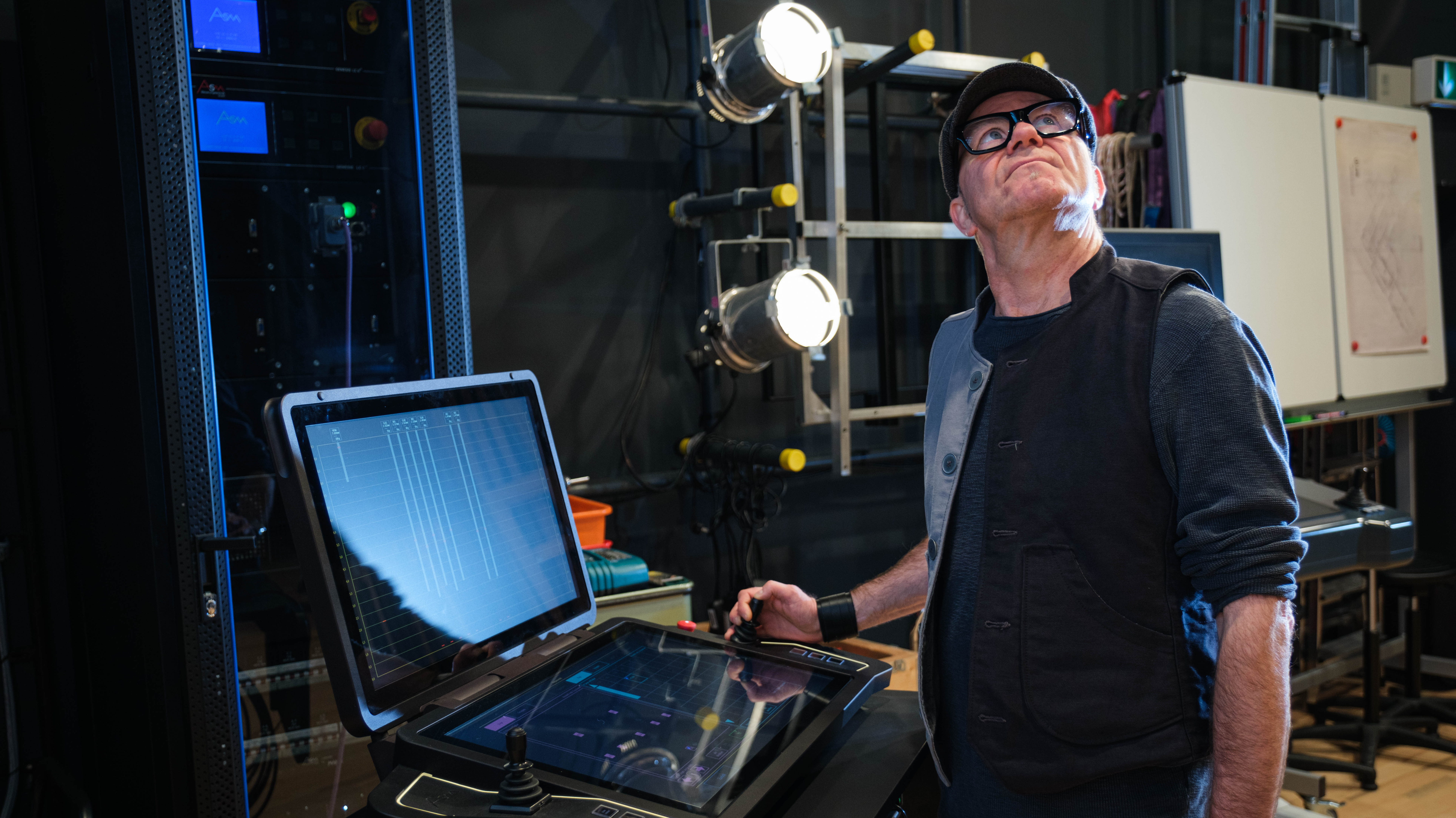 Mann bedient Steuerungsgerät für Lichttechnik und blickt nach oben