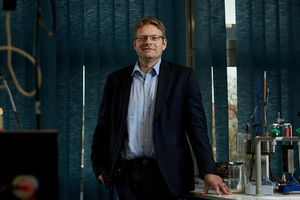 Andreas Modler in einem schwach beleuchteten Labor mit Apparaturen aus der physikalischen Technik