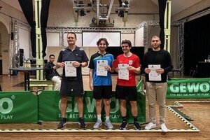 Vier Männer in Sportkleidung posieren mit Urkunden in der Hand