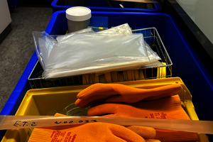 Mehrere bepackte bunte Kisten. Vorne auf liegen gelbe Handschuhe.