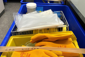 Mehrere bepackte bunte Kisten. Vorne auf liegen gelbe Handschuhe.