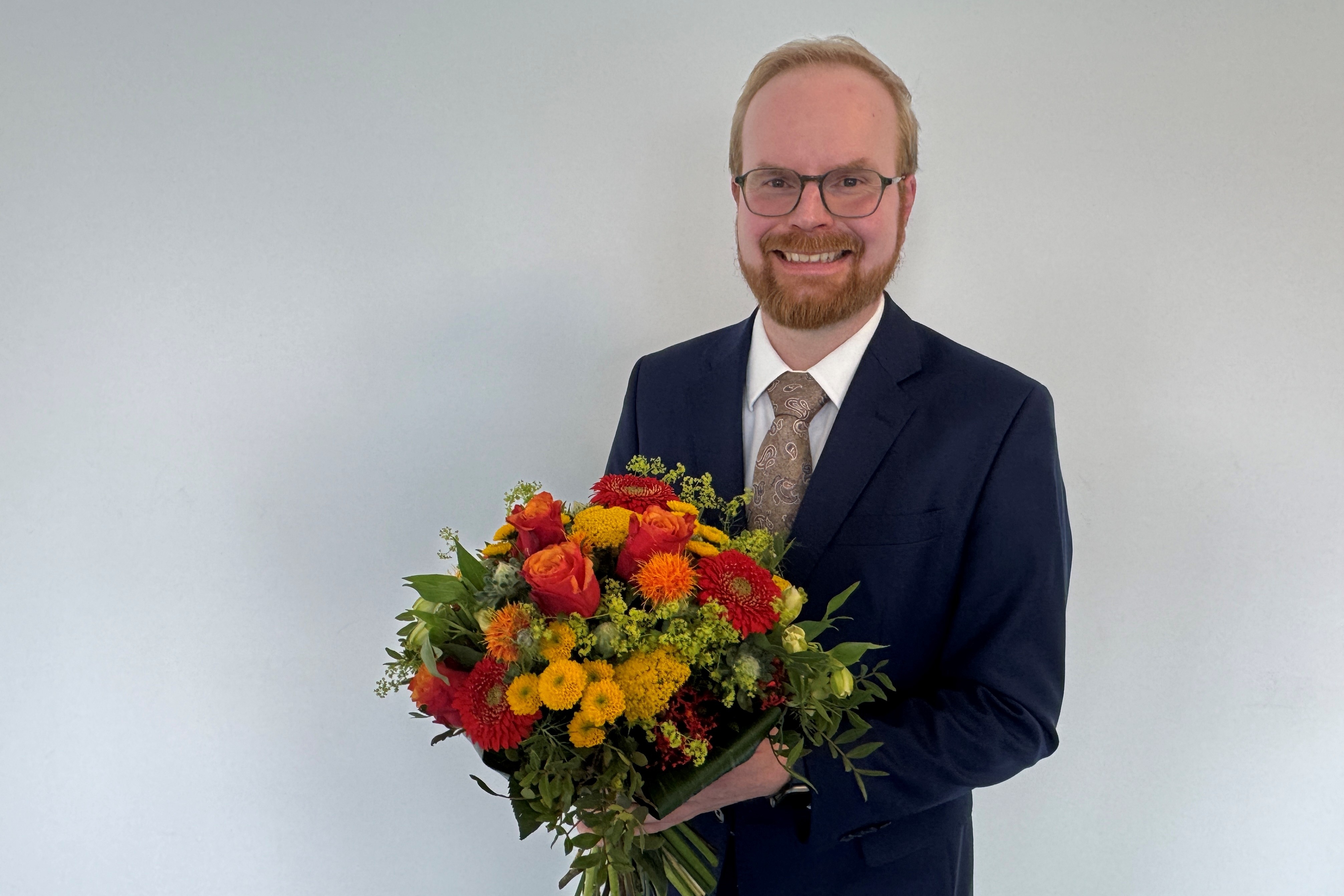 Porträt von Konrad C. Schäfer in Anzug mit Blumenstrauß