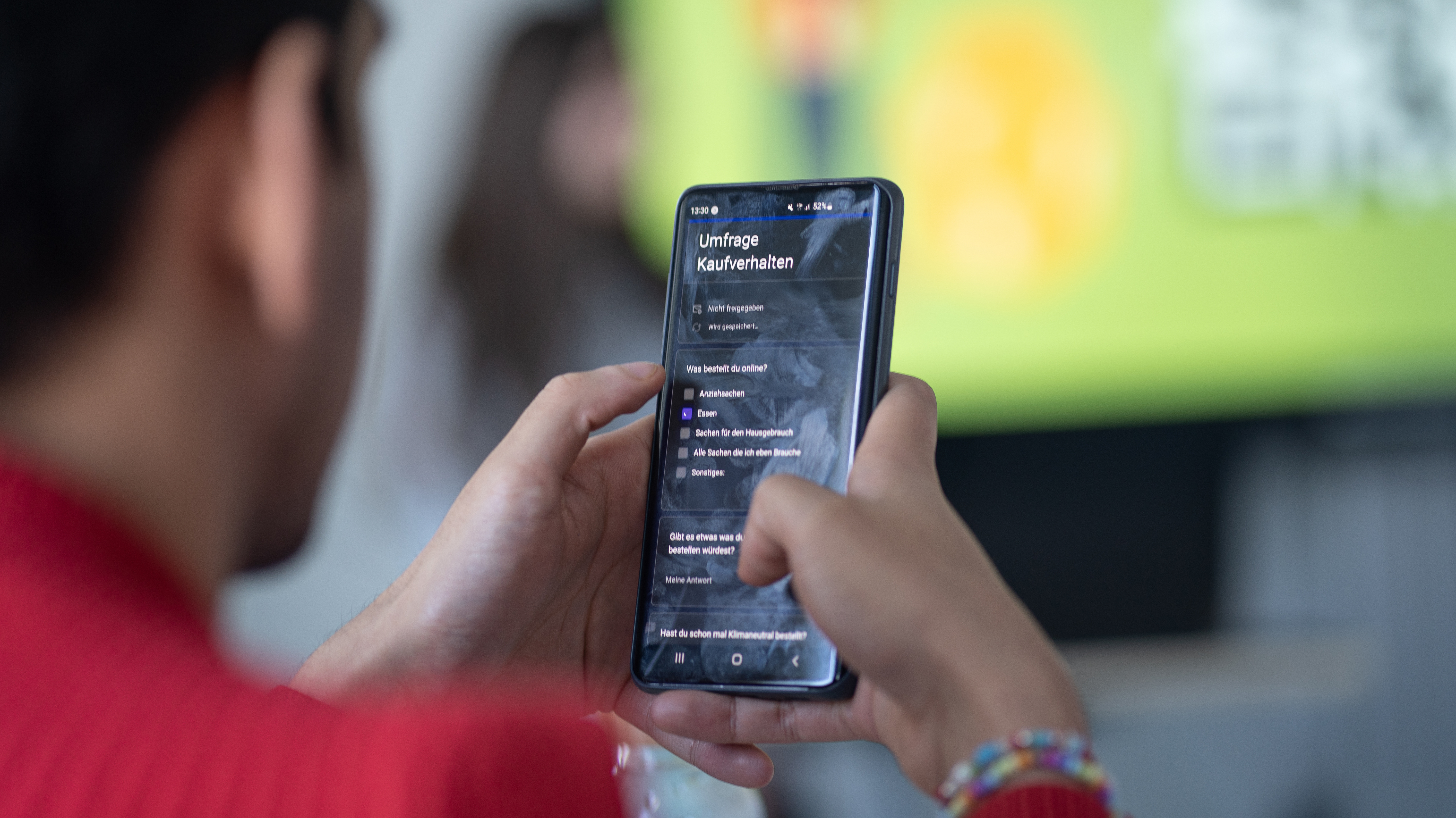 Blick über die Schuler einer Person, die auf dem Handy eine Umfrage zum Kaufverhalten ansieht
