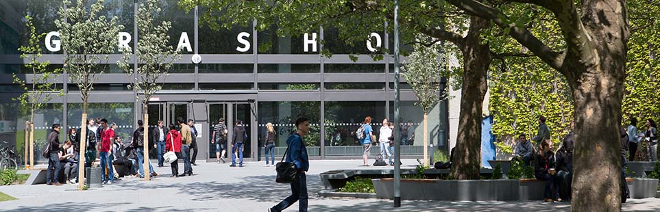 Mehrere Studierende laufen auf dem Campus vor dem Haus Grashof