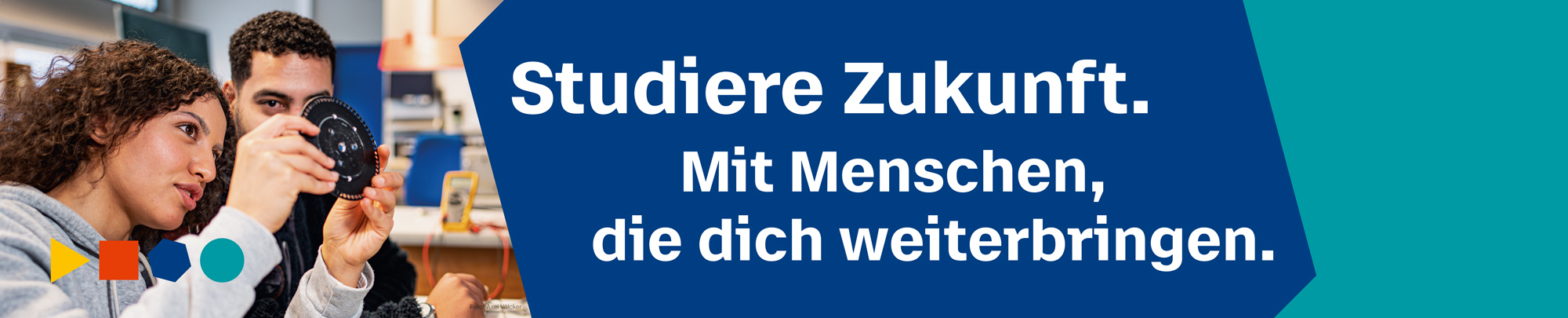 Eine Studentin hält im Labor ein Bauteil in der Hand und betrachtet es gemeinsam mit einem Mitstudierenden. Text: Studiere Zukunft. Mit Menschen, die dich weiterbringen.