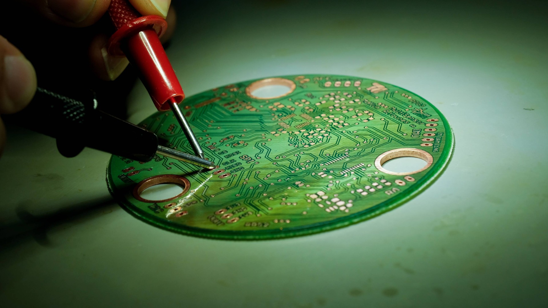 Lötkolben zeigen auf einen runde grüne Platina