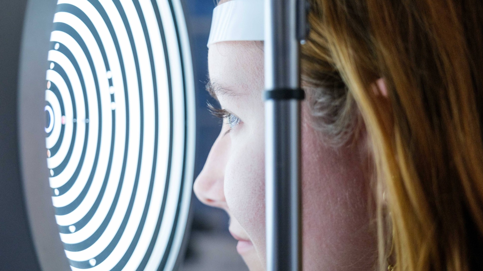 Frau blickt in ein Gerät zur Augenuntersuchung