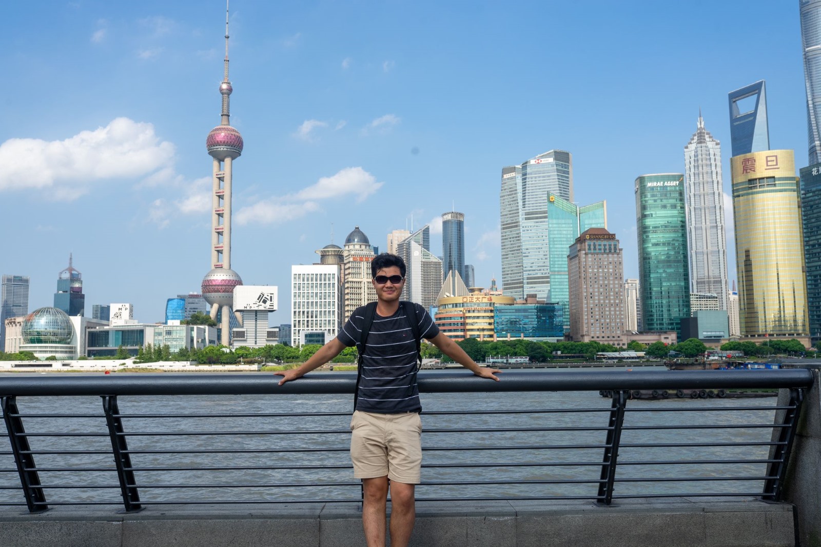 Junger Mann steht vor Skyline in Shanghai