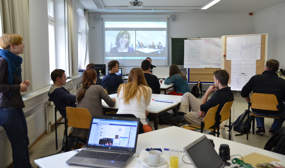 Hybride Lehrveranstaltung mit einer Lehrperson vor Ort und einer per Webkonferenz zugeschalteten Person.