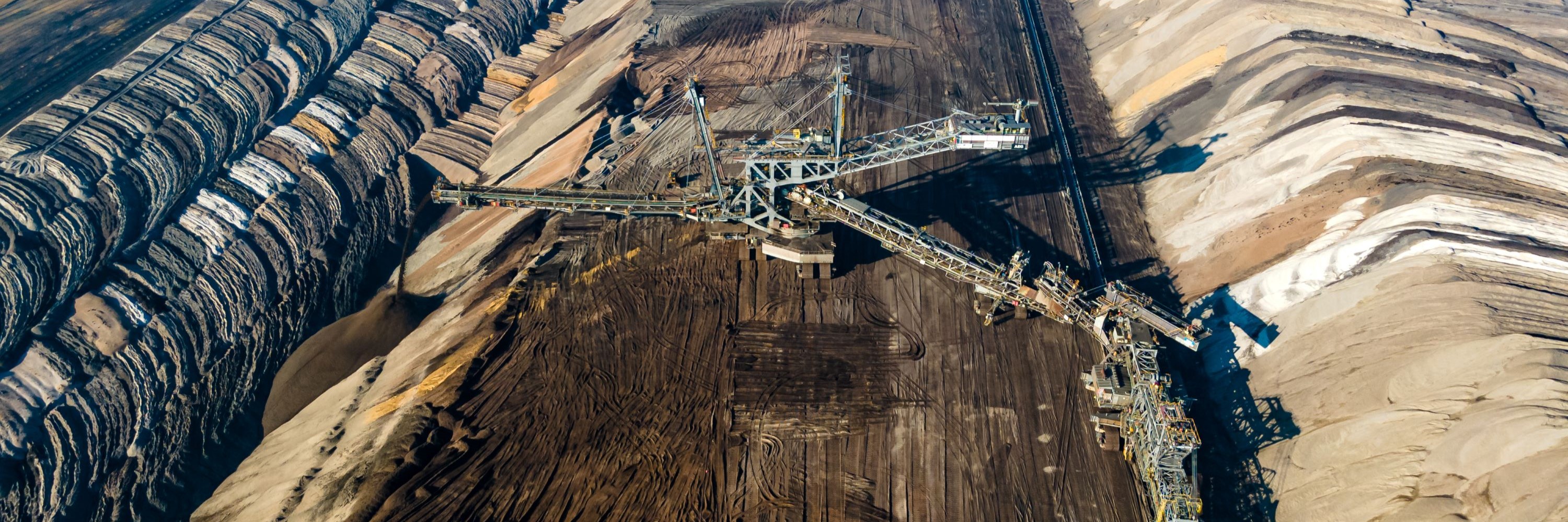 Rohstoffsektor Vogelperspektive auf einen Tagebau, in der Mitte ein riesiger Schaufelradbagger.