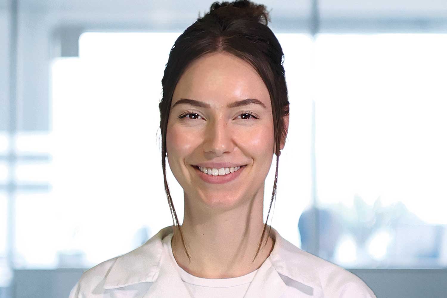 Die Porträtaufnahme zeigt Julia Viktoria Wesolowski in einem Labor mit weißem Kittel