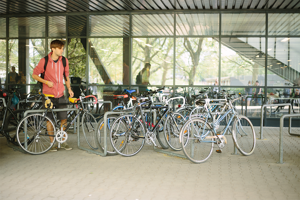 Ein BHT-Student schließt sein Fahrrad vor Haus Bauwesen an.