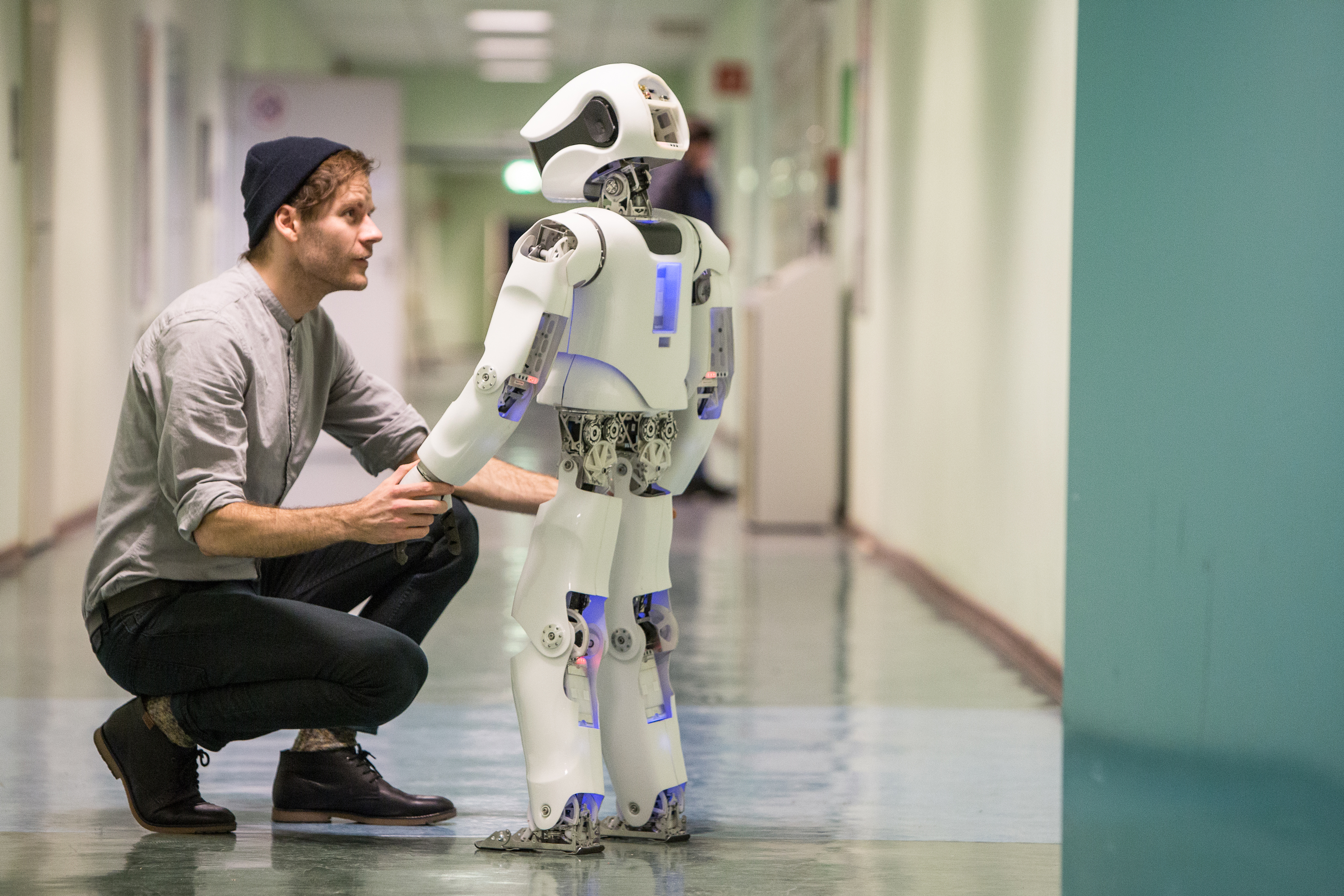 Ein Mann und ein Roboter halten sich an den Händen uns sehen sich an