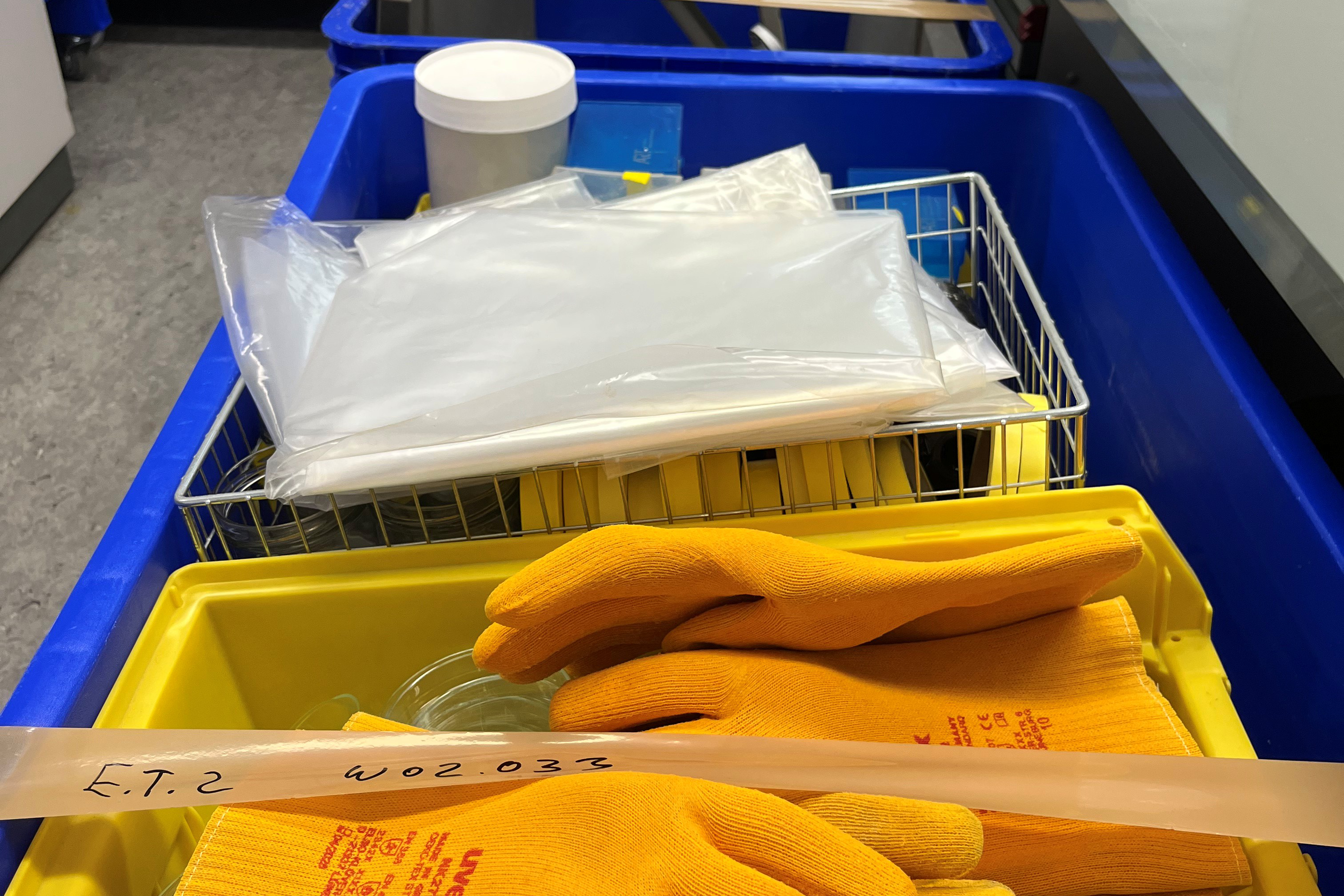 Mehrere bepackte bunte Kisten. Vorne auf liegen gelbe Handschuhe.