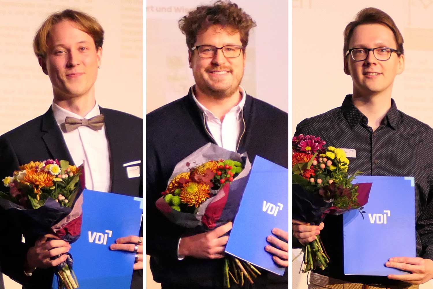 Drei festlich gekleidete Männer halten jeweils eine Auszeichnung und einen Blumenstrauß in der Hand