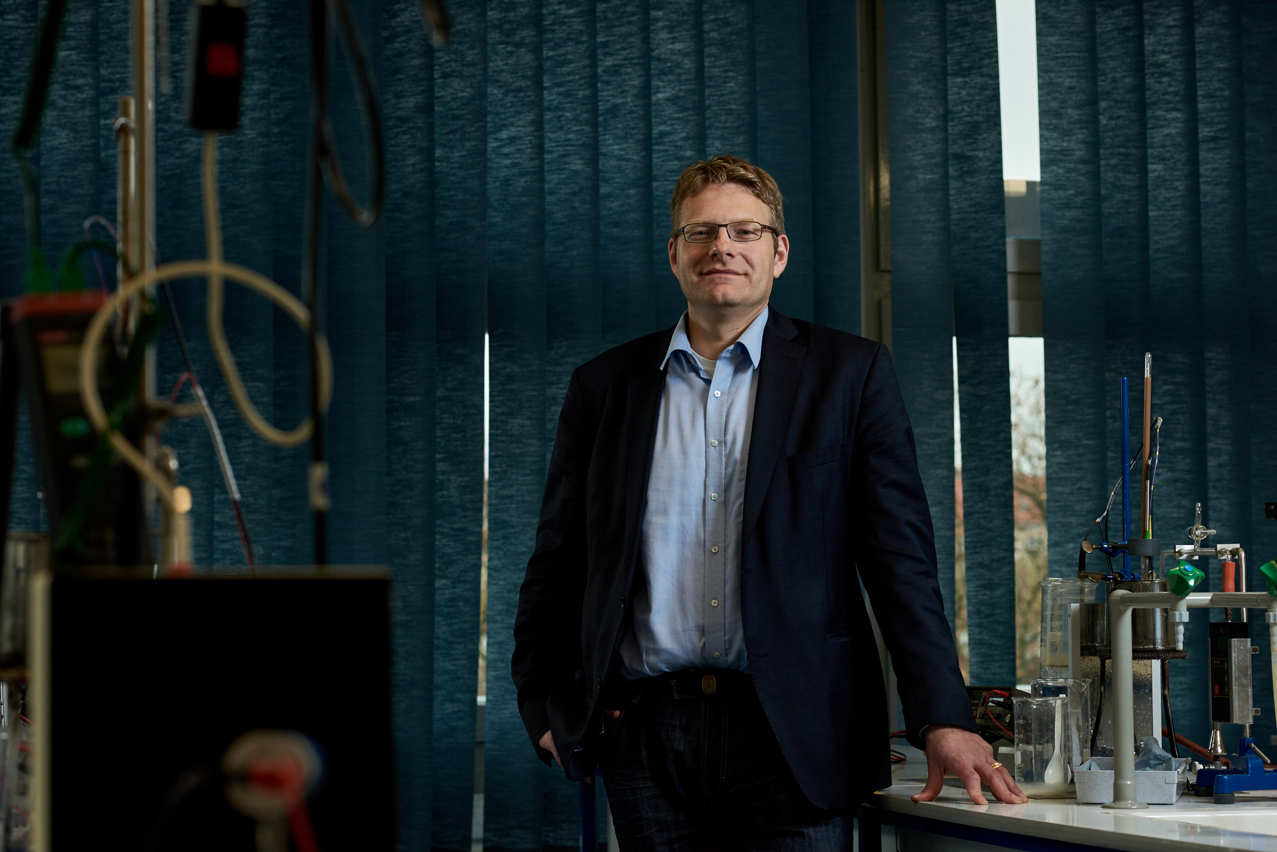 Andreas Modler in einem schwach beleuchteten Labor mit Apparaturen aus der physikalischen Technik