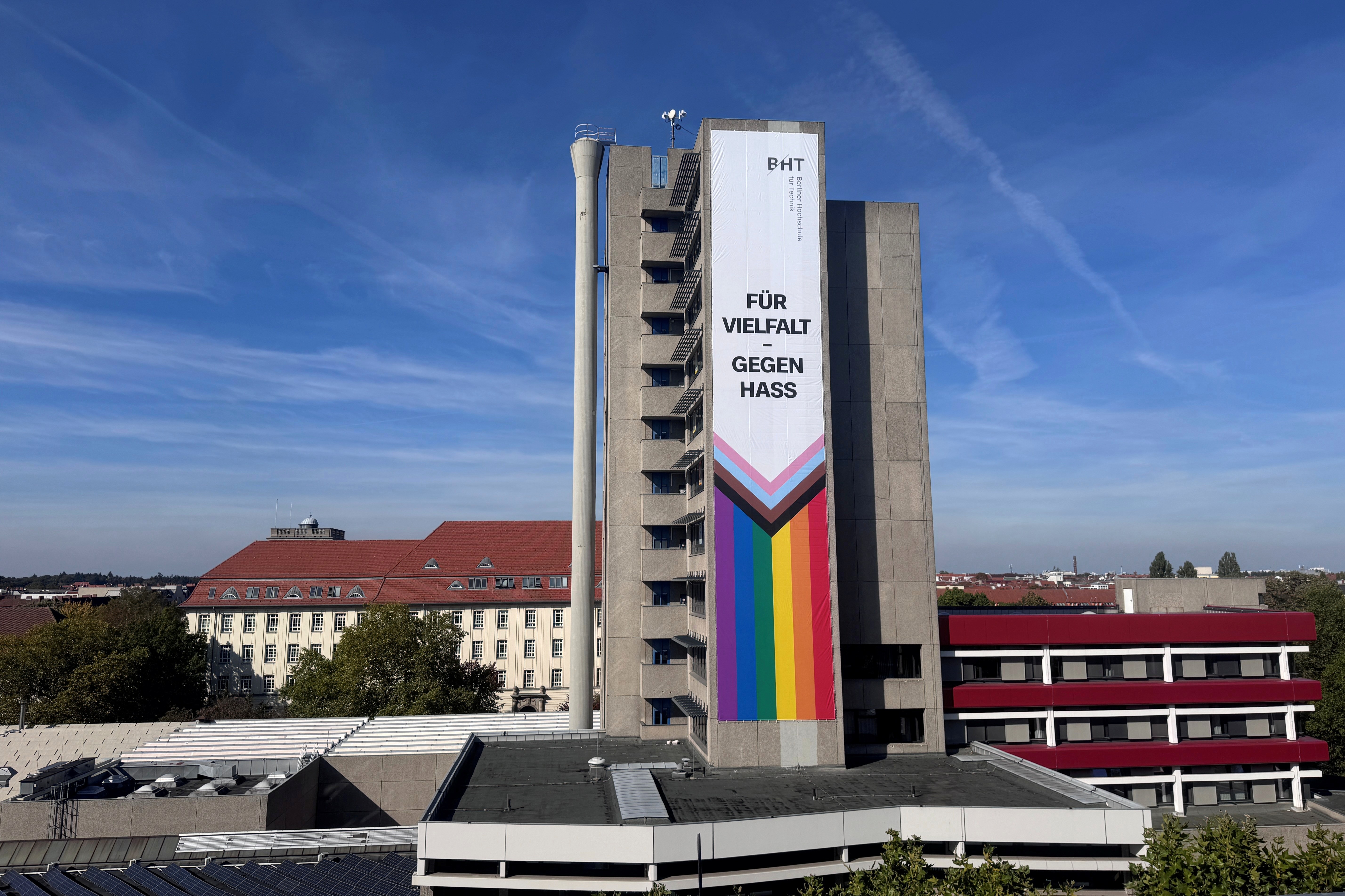 Am Turm des Hauses Grashof auf dem BHT-Campus hängt ein Banner mit der Aufschrift Für Vielfalt - gegen Hass und Progress-Pride-Flagge 