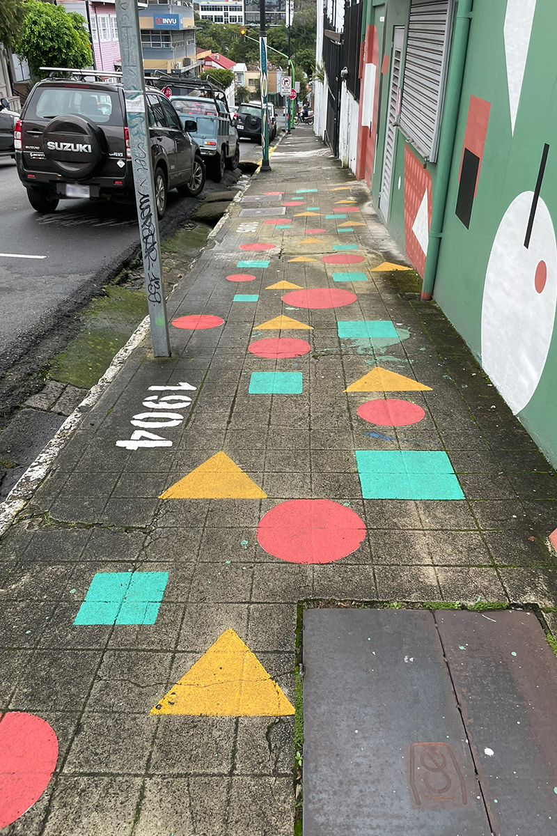 Ein Gehweg, der mit bunten Kreisen, Vierecken und Dreiecken gestaltet ist.