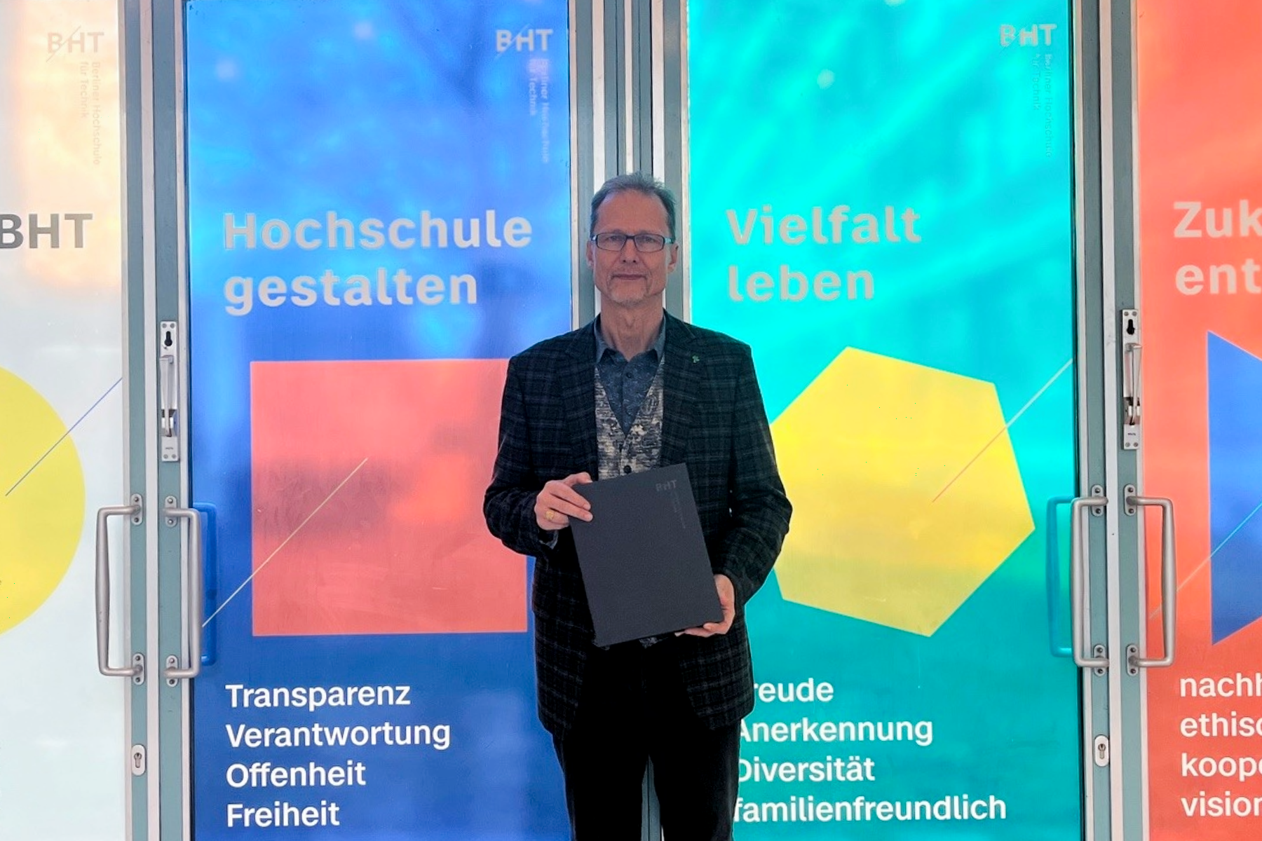 Mann steht vor bodentiefen Glasfenster, die mit bunten Folien beklebt sind