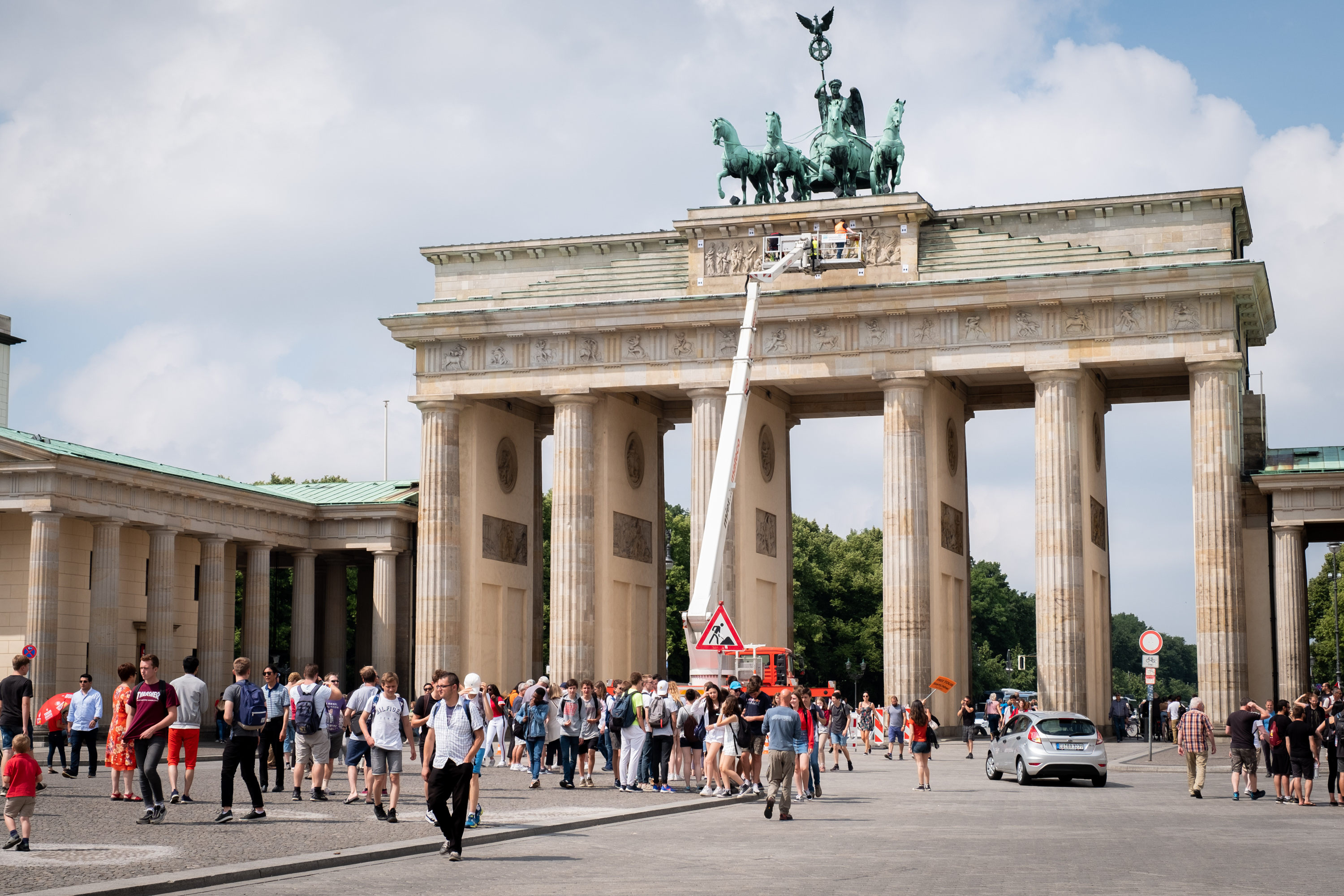 Menschenansammlung vor dem Brandenburger Tor, an dem mithilfe eines Steigerwagens Vermessungen in großer Höhe vorgenommen werden