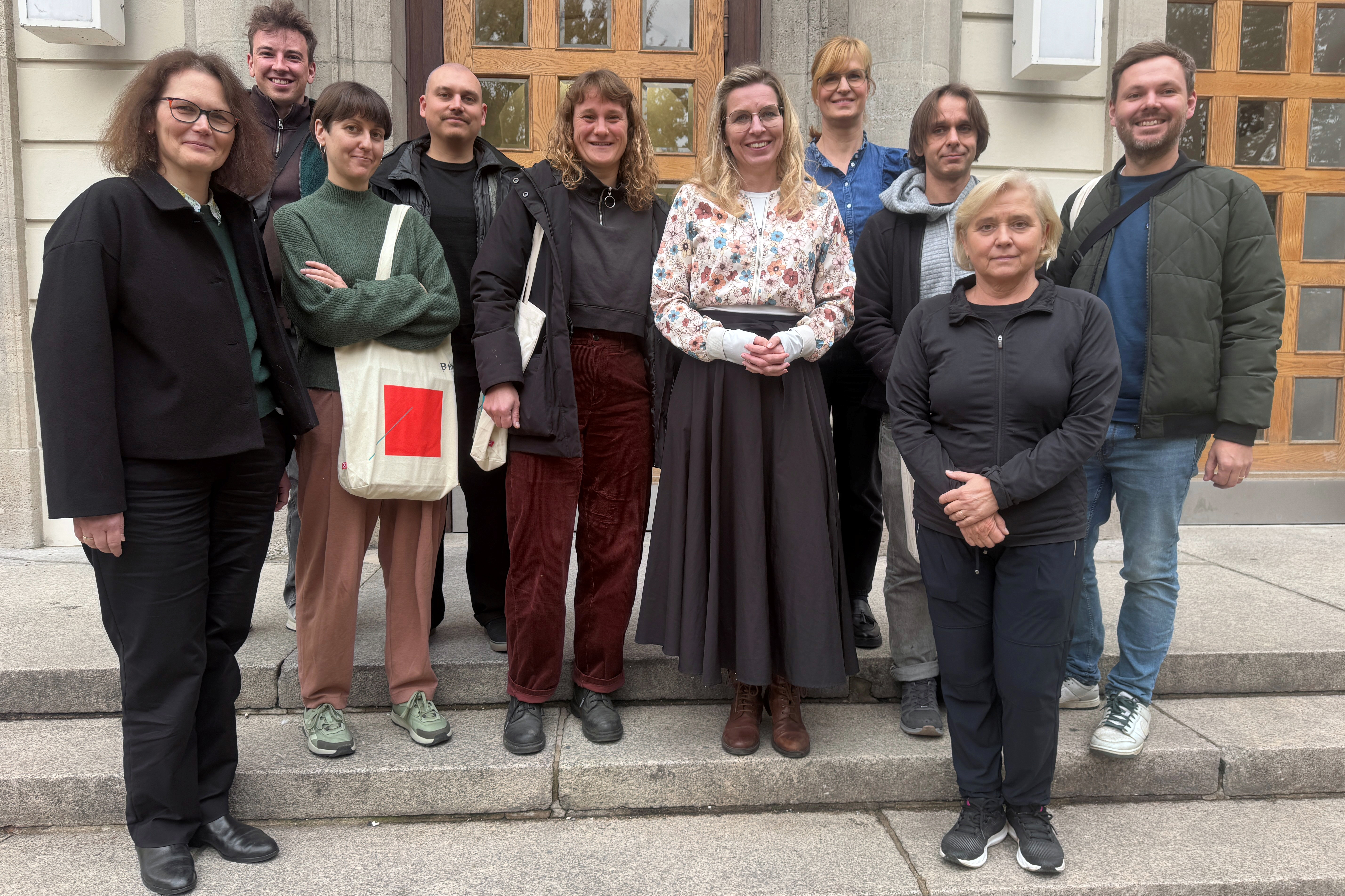 Zehn Menschen posieren vor dem BHT-Gebäude