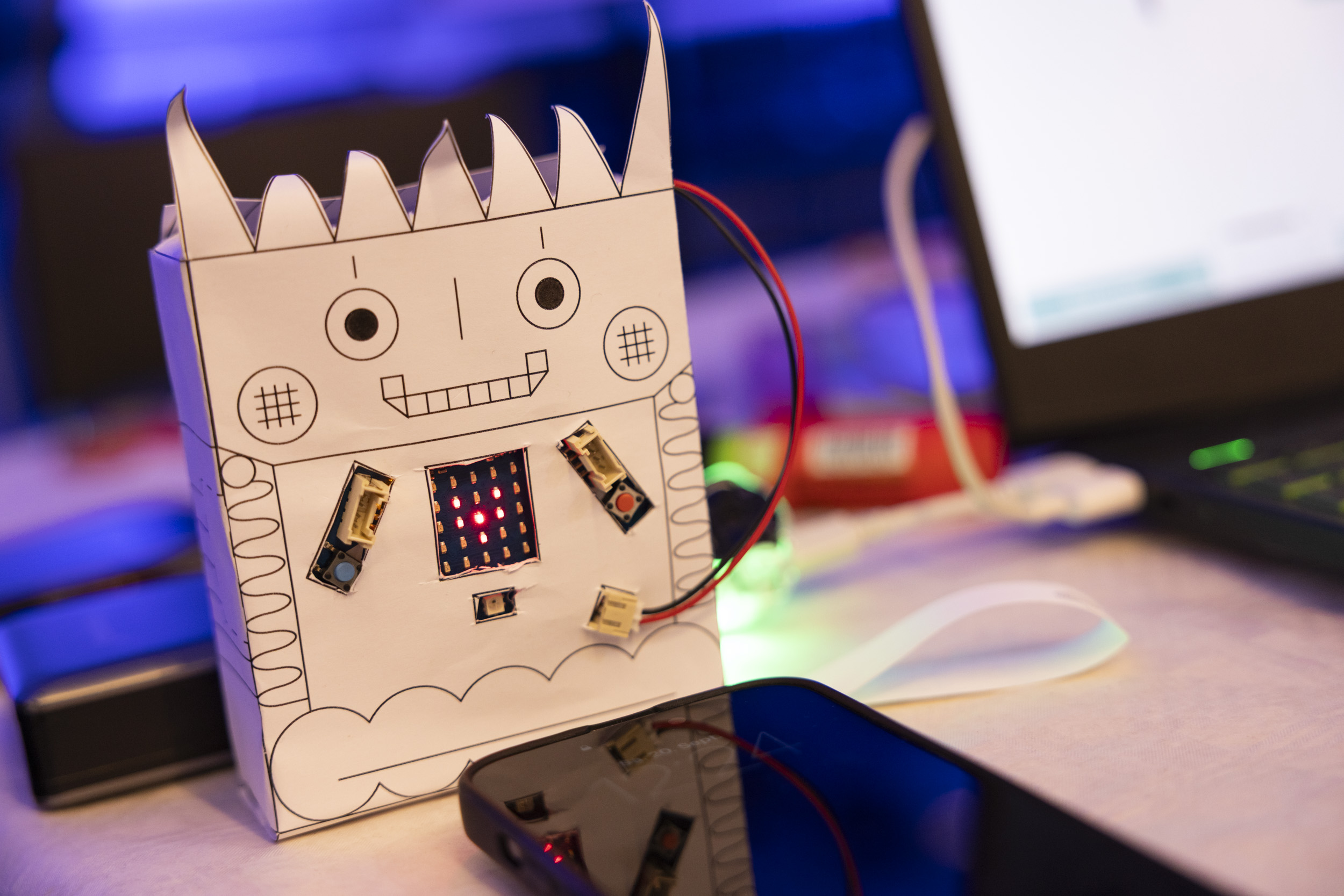 Lustiger Roboter aus Pappe, der mit einem Laptop verbunden ist