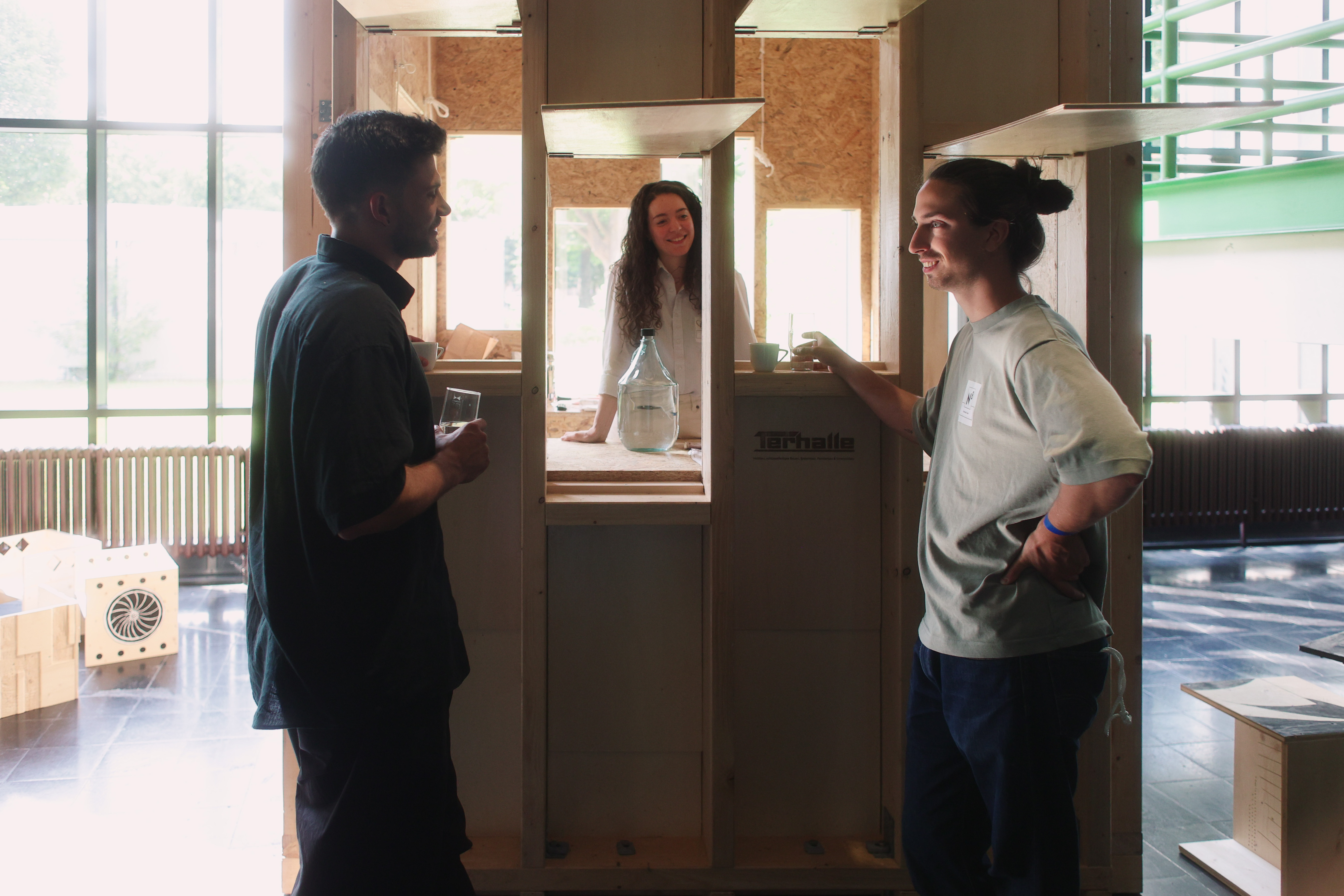 Drei Personen stehen bei einer Holzkonstruktion