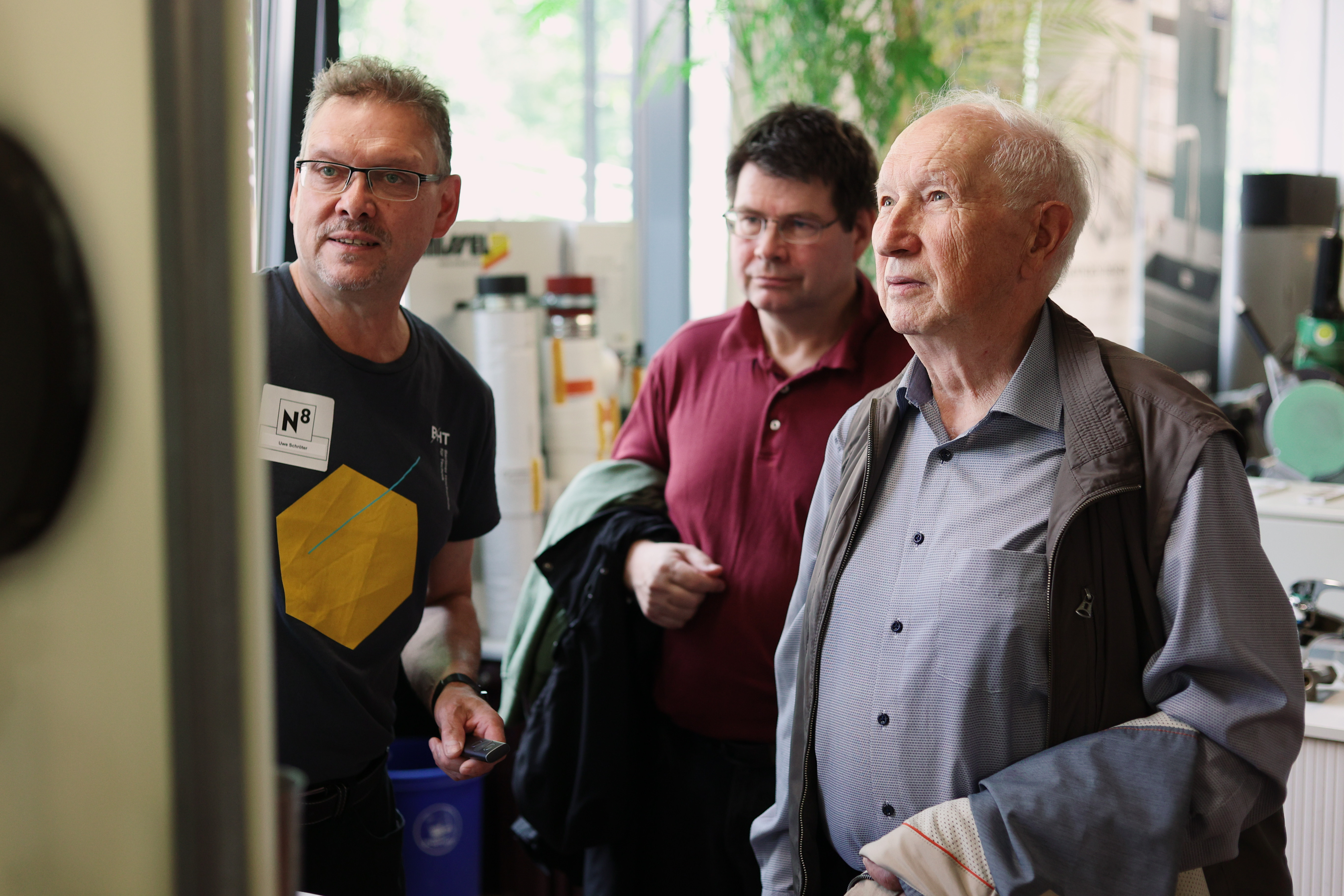 Drei Männer betrachten gespannt einen Pinnwand