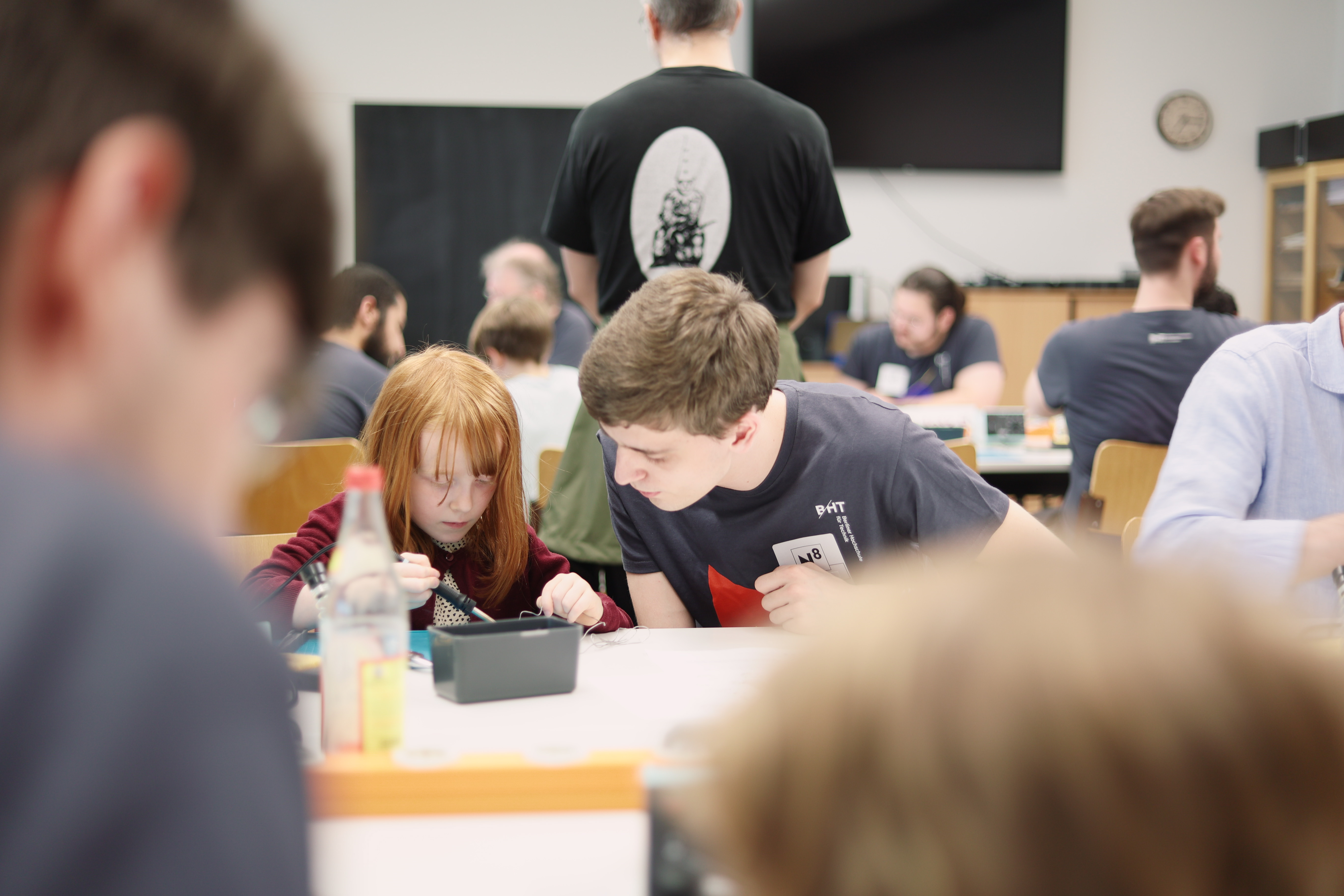 Ein Mädchen macht unter Anleitung eine Lötübung