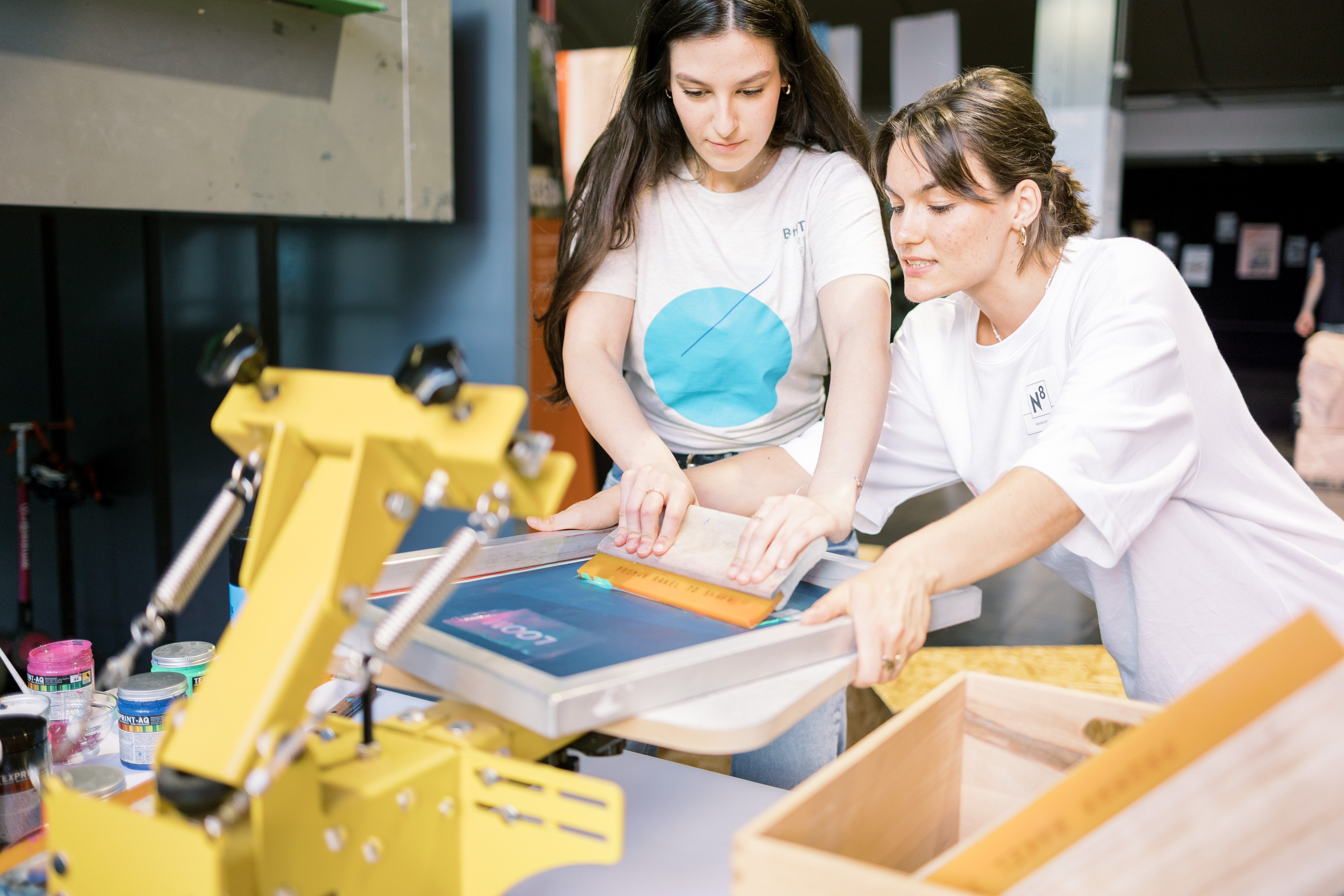 Zwei Frauen bestreichen Druckschablone mit Farbe