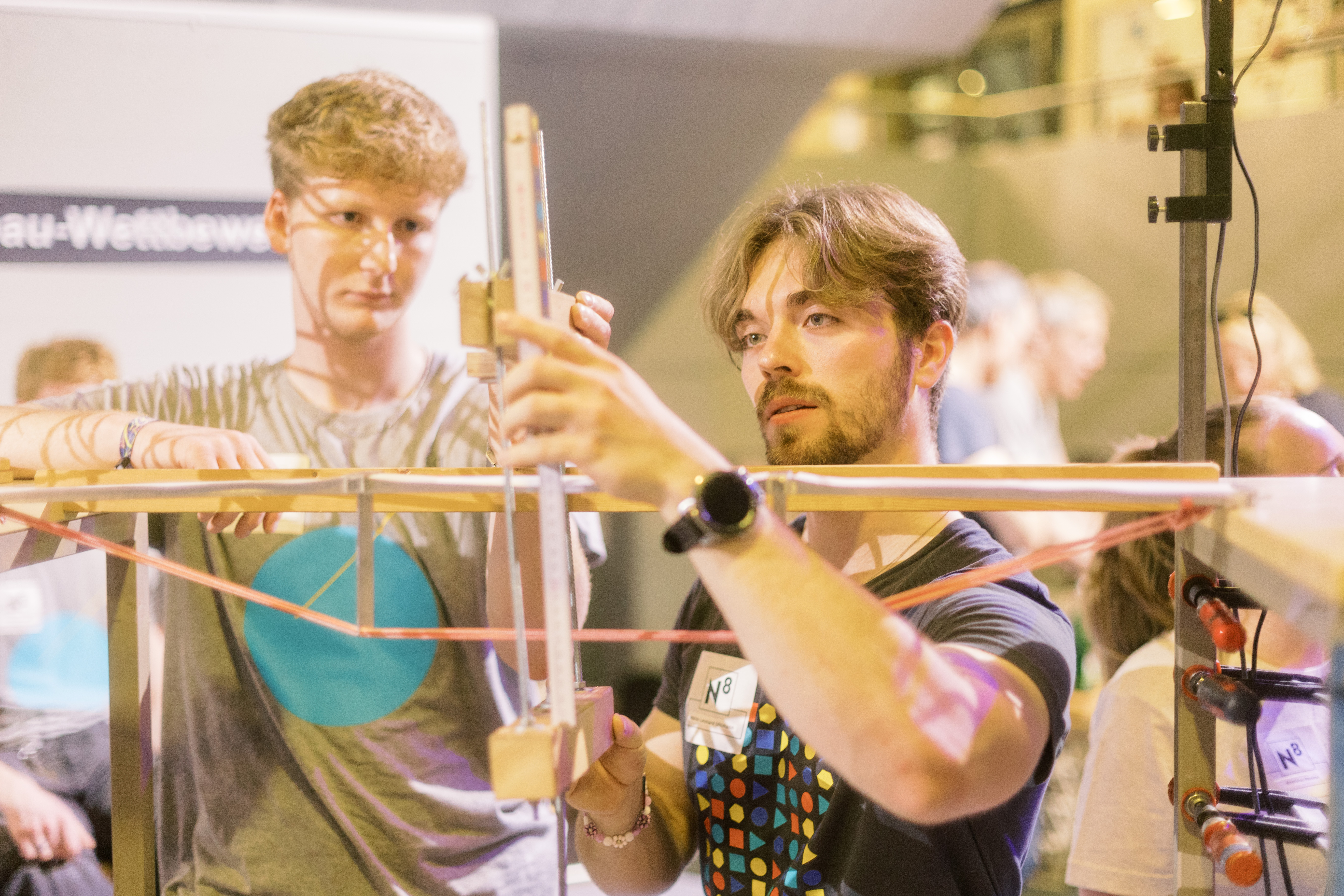 Zwei Männer bauen Brückenmodell an Testvorrichtung auf