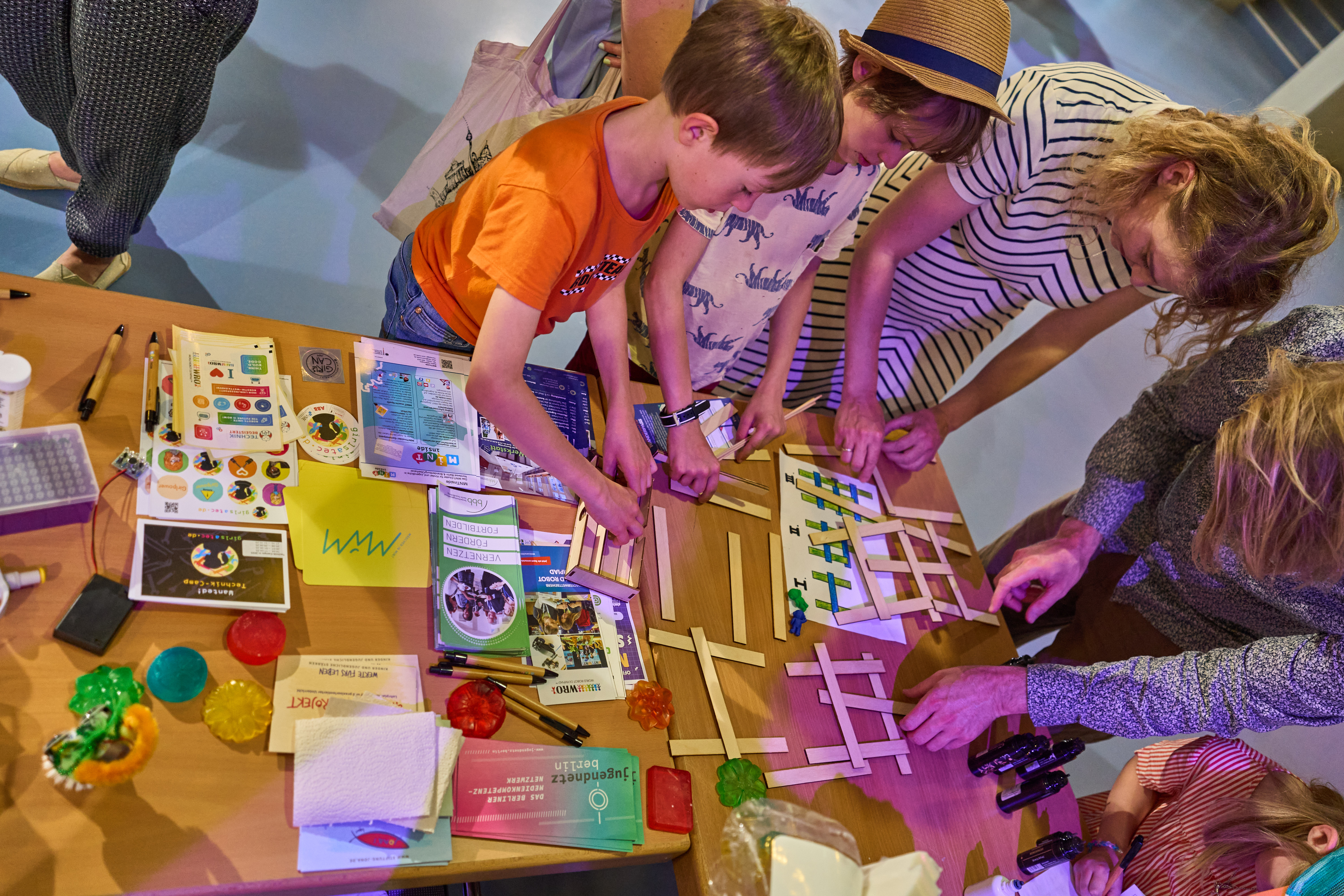 Draufsicht auf einen Stand, an dem mehrere Personen gemeinsam etwas zusammenbauen.