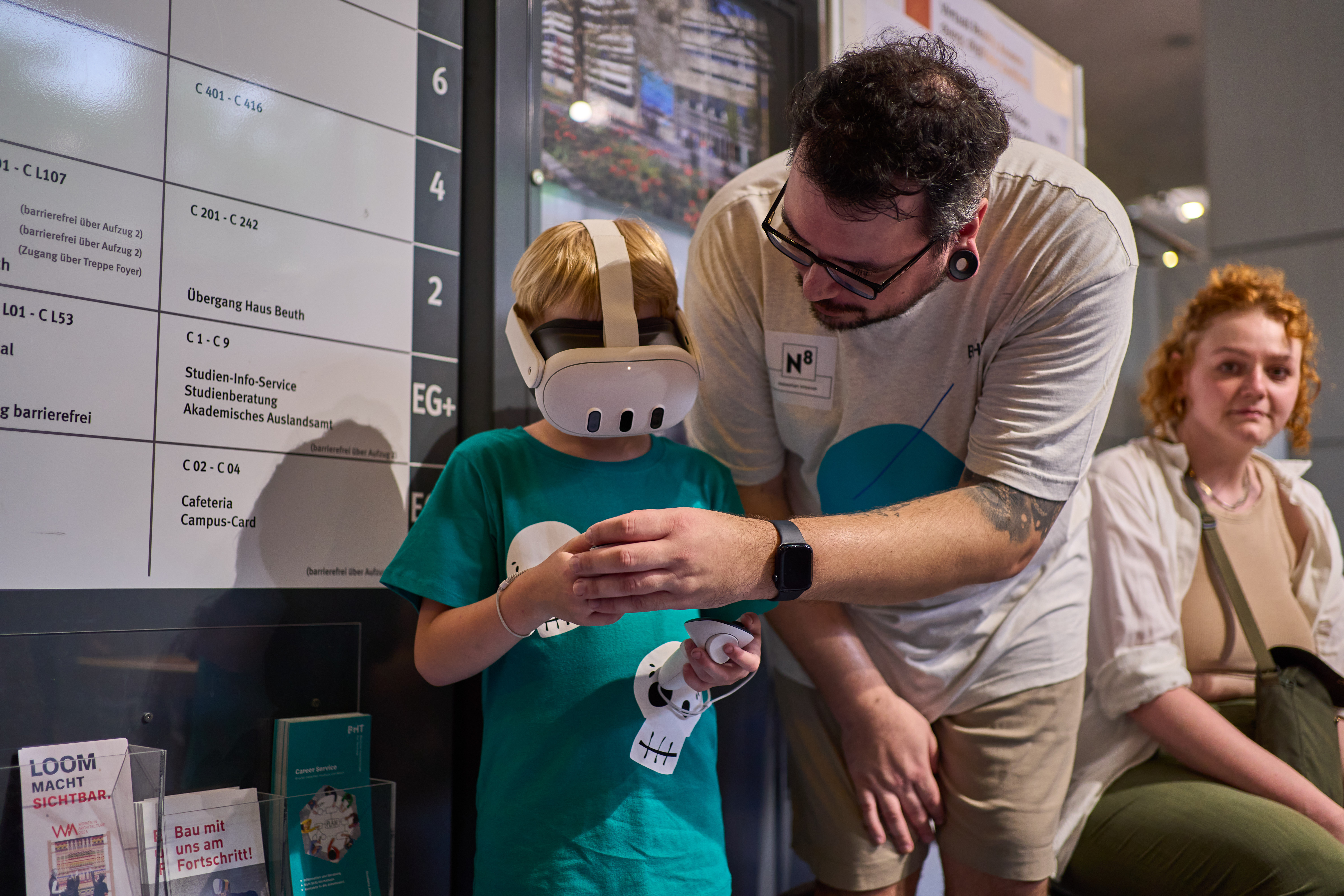 Kind mit VR-Brille, dem ein Mitarbeiter etwas erklärt.