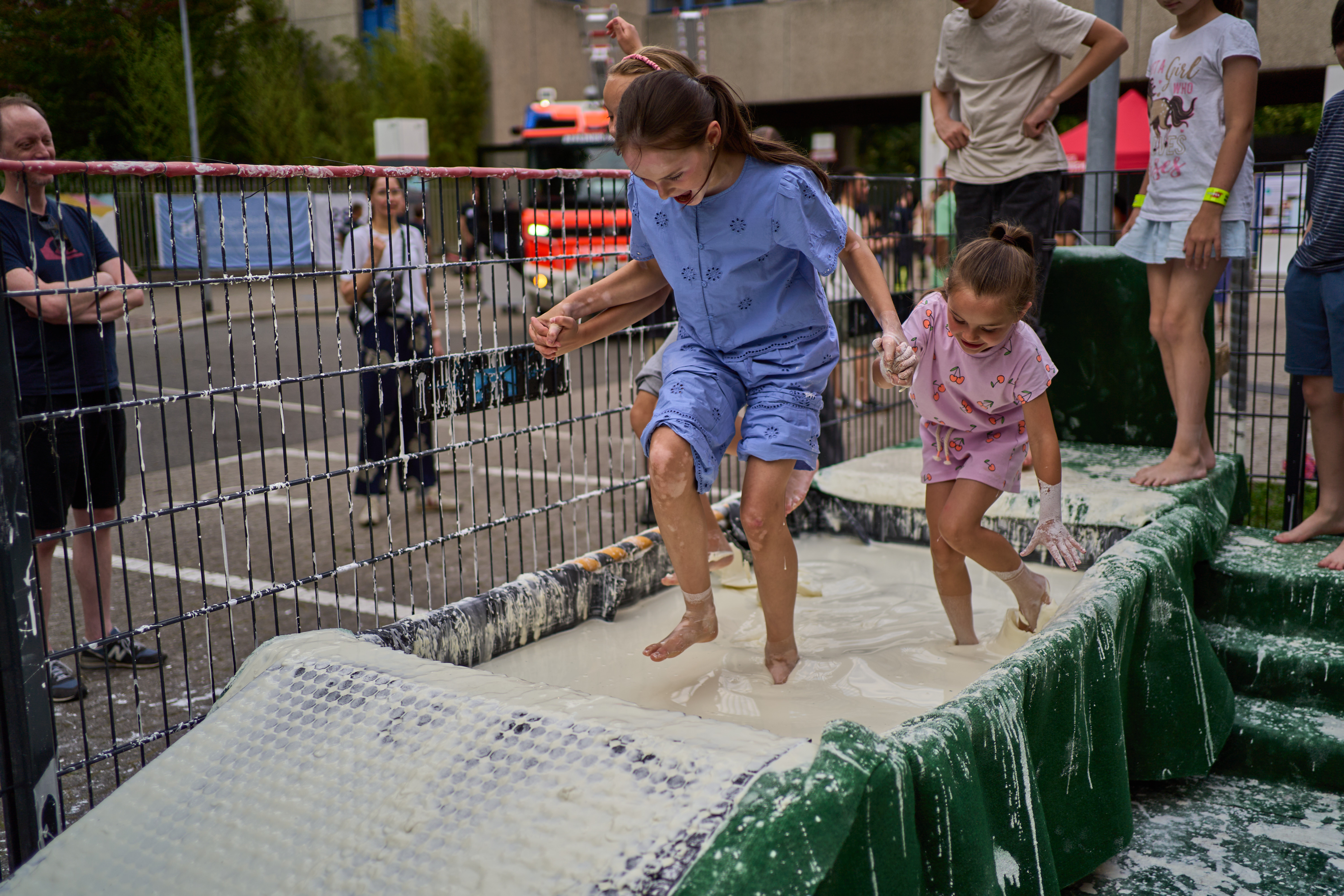 Zwei Kinder laufen über eine zähflüssige Mischung in einem Becken.