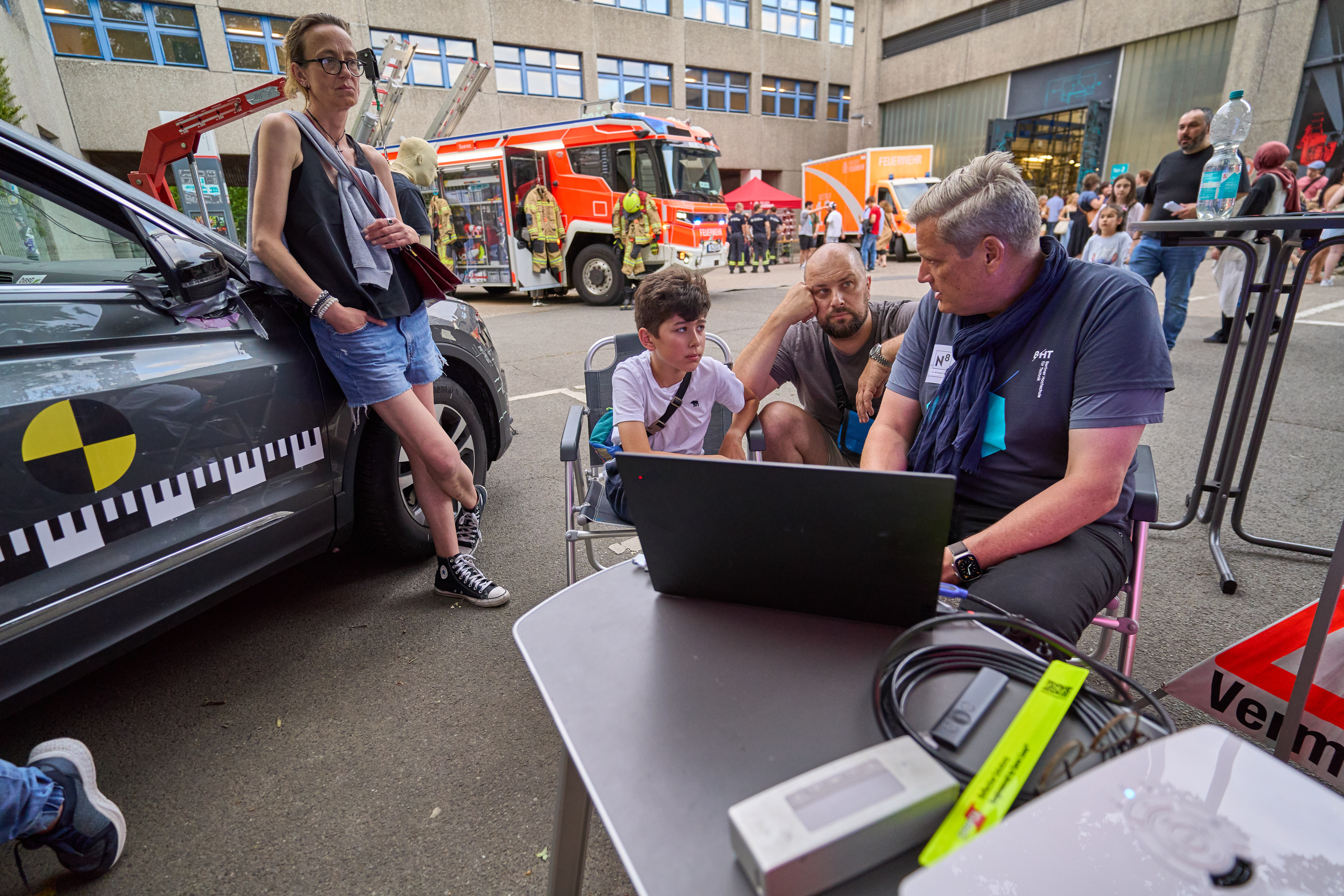 Mitarbeiter zeigt Besuchern etwas am Laptop und beantwortet Fragen.