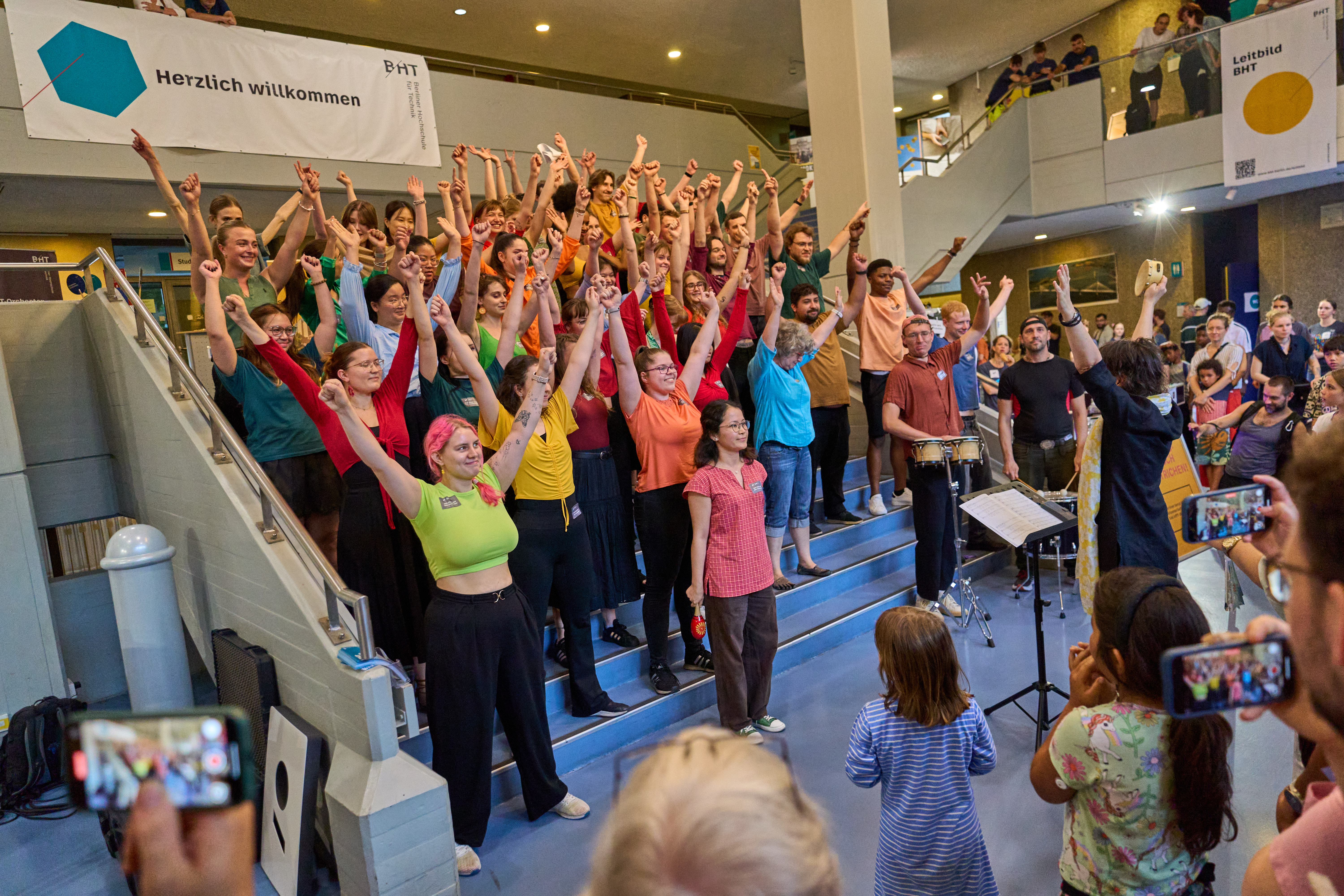Menschenmenge posiert auf einer Treppe vor Publikum.