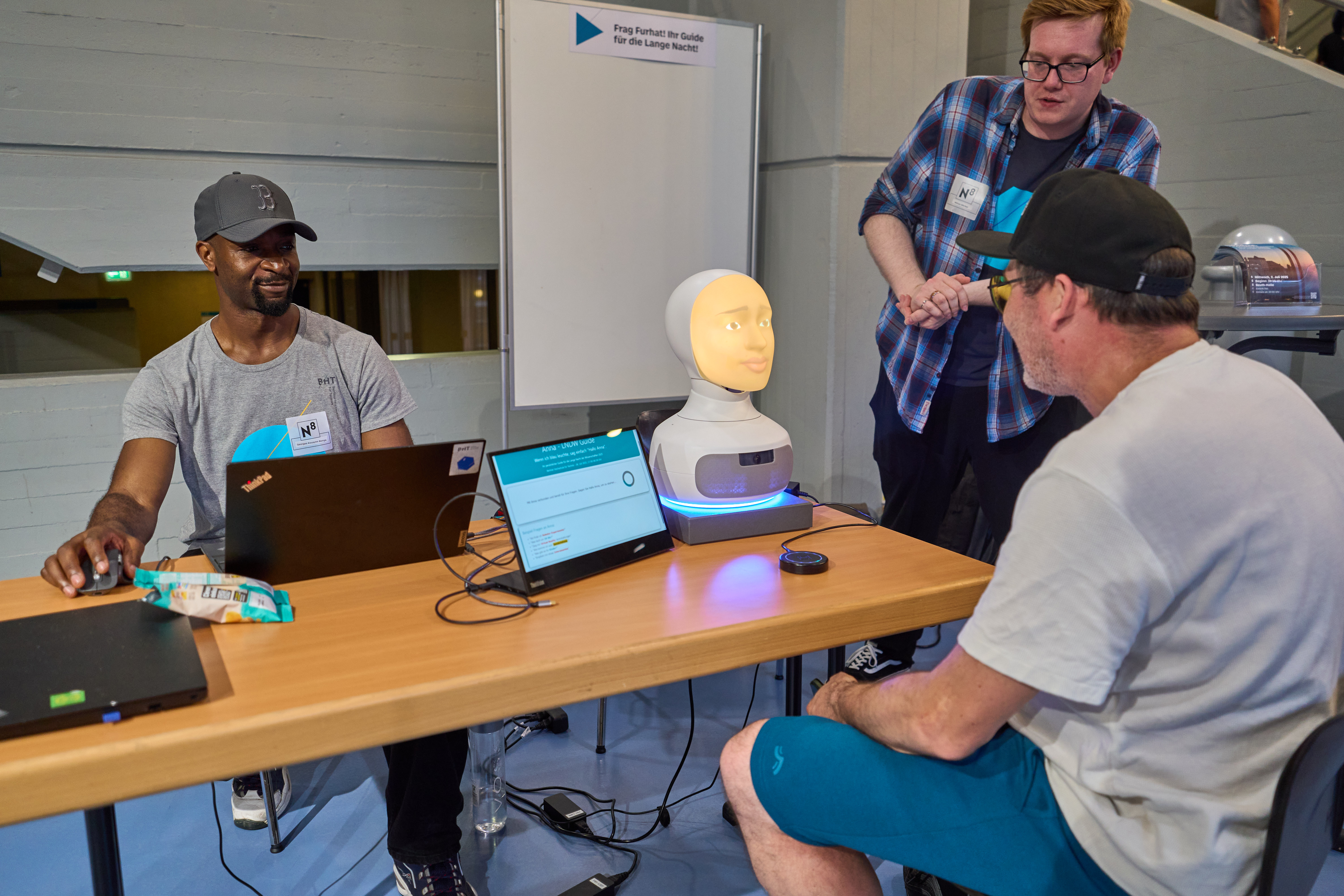 Besucher sitzt vor einem Roboter